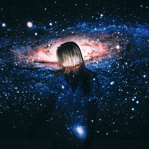 A figure standing before a projected galaxy