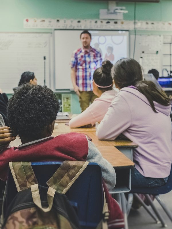 Students at desks facing a teacher in a classroom