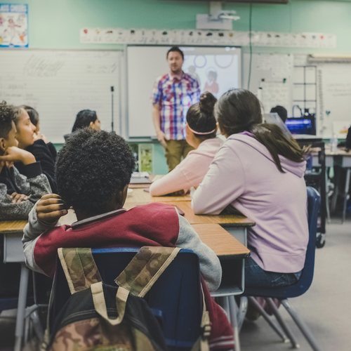 Students at desks facing a teacher in a classroom
